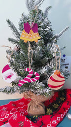 Festive holiday ornaments shaped like traditional candy canes, displayed with green pine branches and red ribbon.