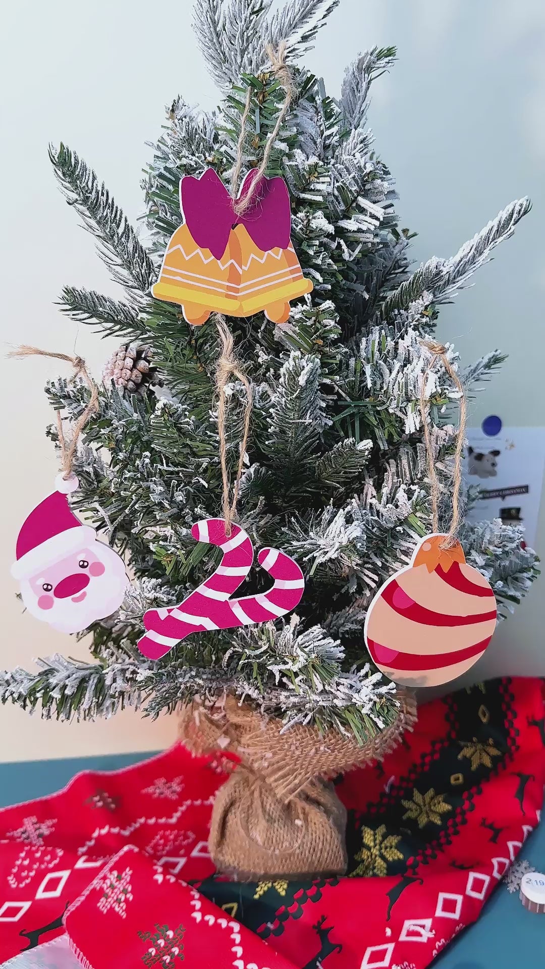 Festive holiday ornaments shaped like traditional candy canes, displayed with green pine branches and red ribbon.