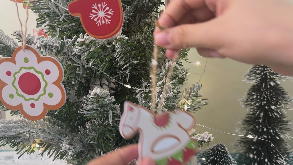 Cozy holiday workshop scene with Christmas ornaments on display, festive decorations, warm lighting, and a crafting table with tools and materials.
