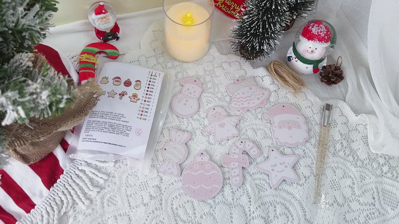 Festive Christmas ornaments in red, gold, and green, spelling out “Sweet Noel Joy,” hanging on a decorated holiday tree.