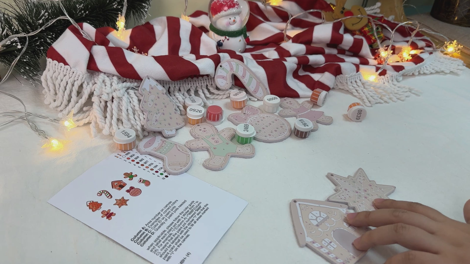 Colorful gingerbread-themed Christmas ornaments hanging on a festive tree, featuring candy cane stripes and cheerful designs.