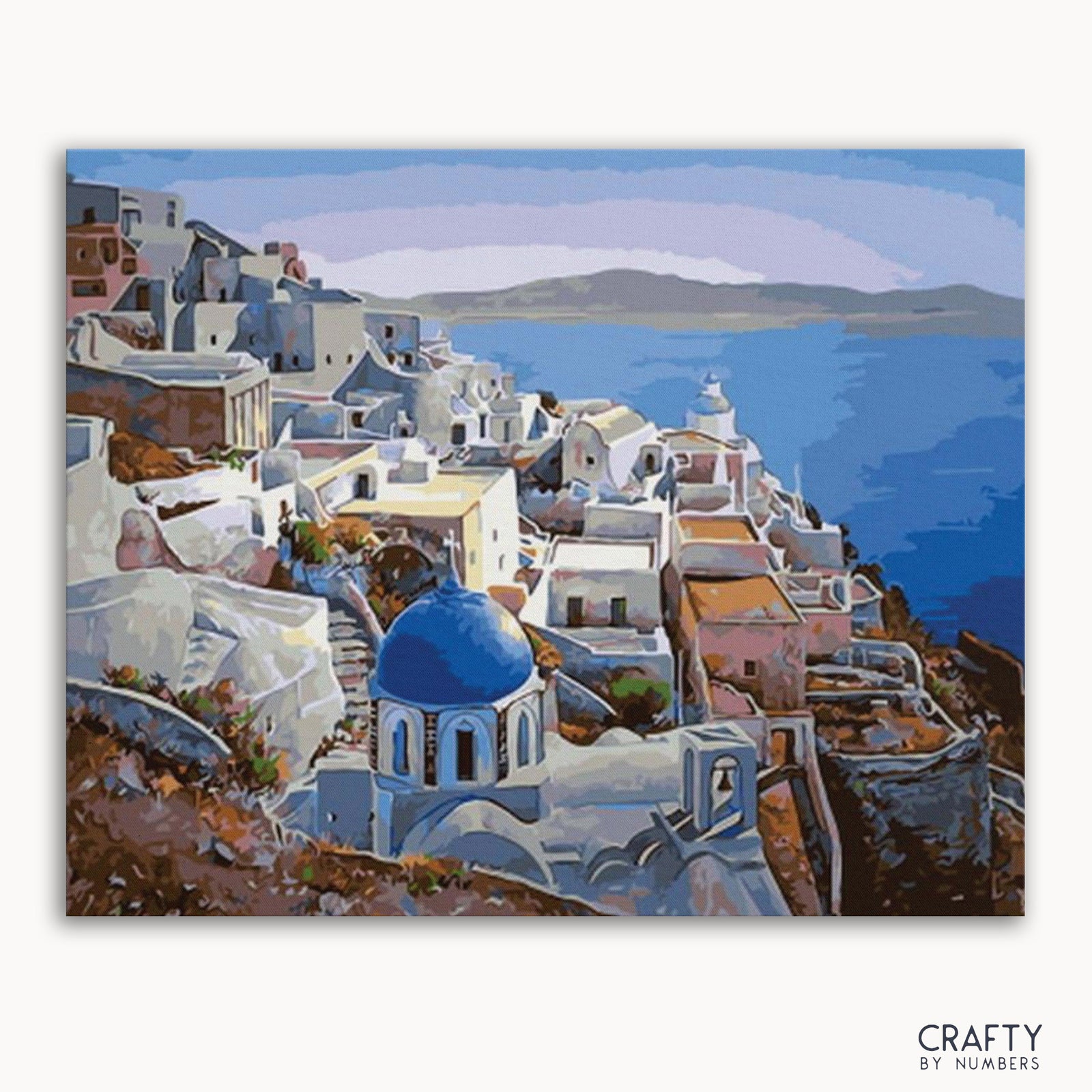 Ein Malen-nach-Zahlen-Set, das eine Santorini-Landschaft mit weißen Gebäuden und einer blauen Kuppel auf einer Leinwand darstellt, gebrandet von Crafts by Numbers.