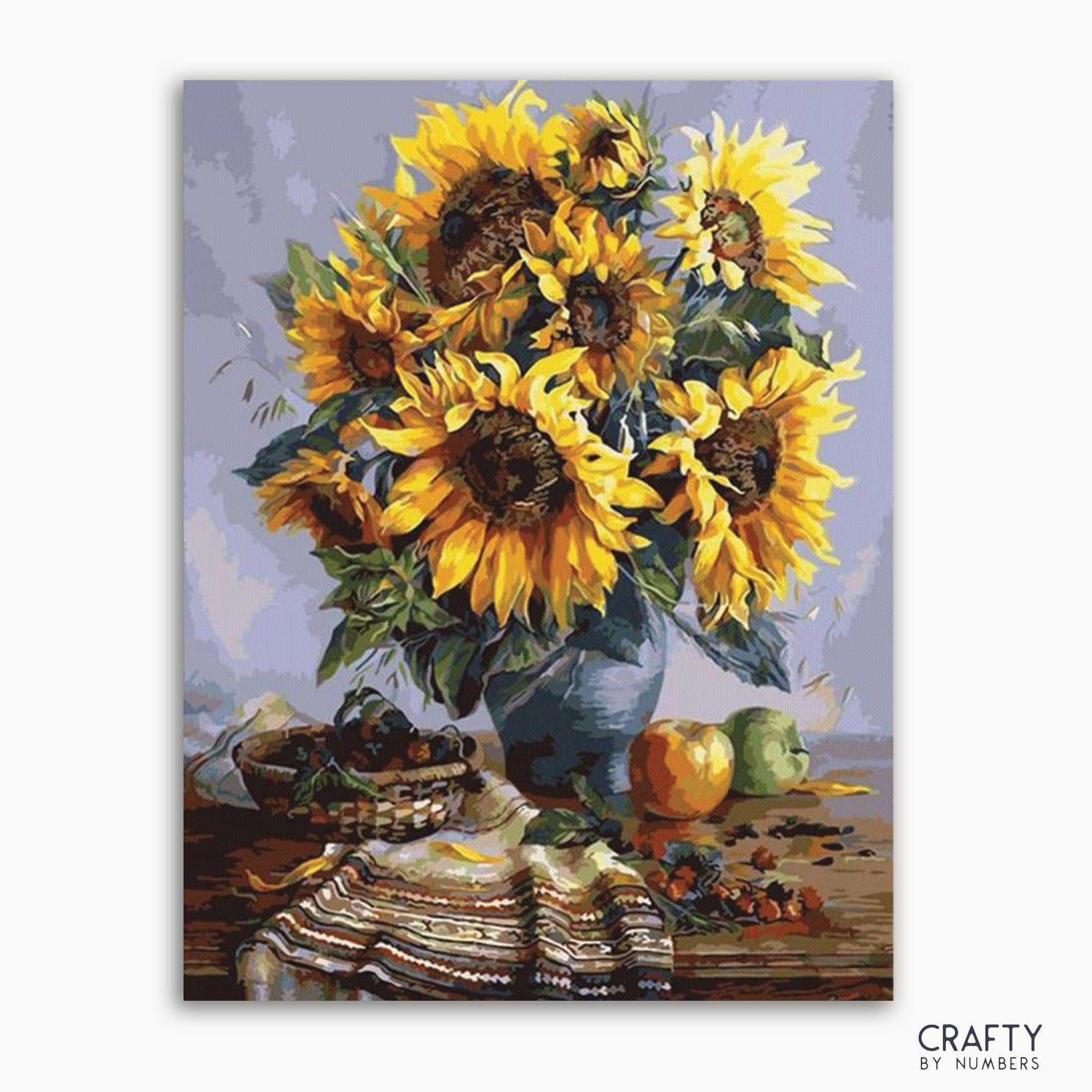 A paint-by-numbers kit image featuring a vase of sunflowers with fruits and a checkered cloth on a table.
