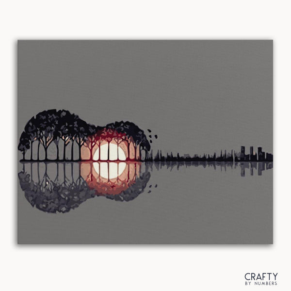 A paint by numbers kit with a silhouette of a guitar filled with a sunset-like design, surrounded by trees and water.