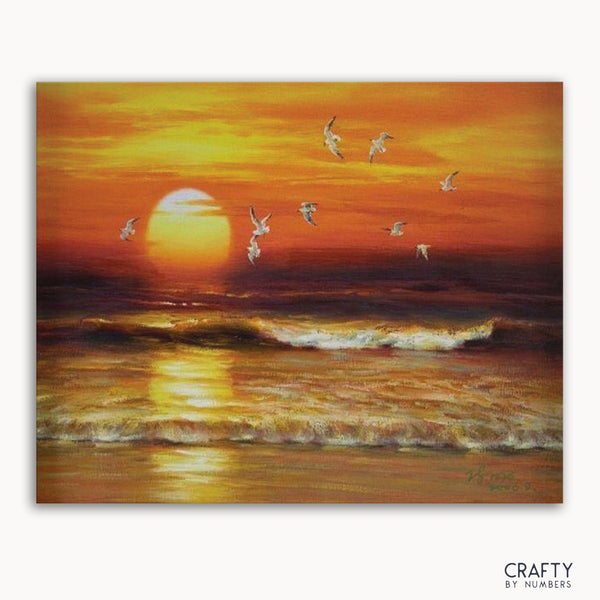 A paint-by-numbers kit image featuring a sunset with waves and birds in flight.