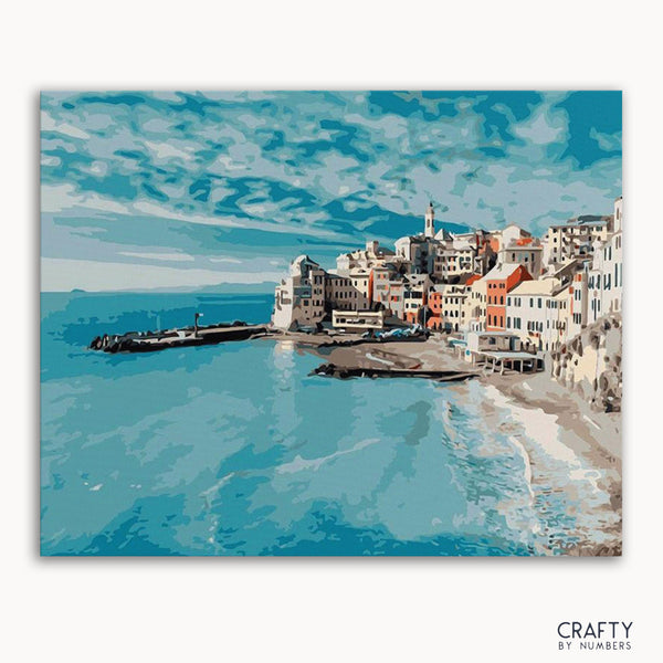 A paint-by-numbers kit depicting a cityscape by the ocean with blue skies and buildings lining the coast.