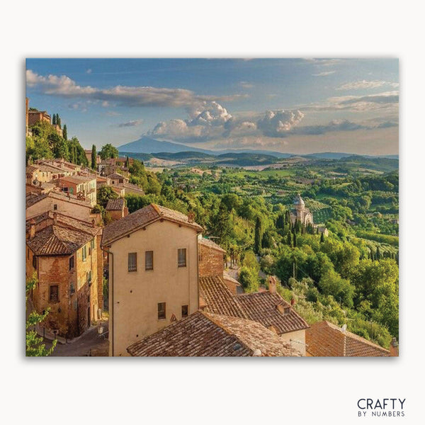 A paint-by-numbers kit image featuring a town in a valley with greenery and hills in the background.