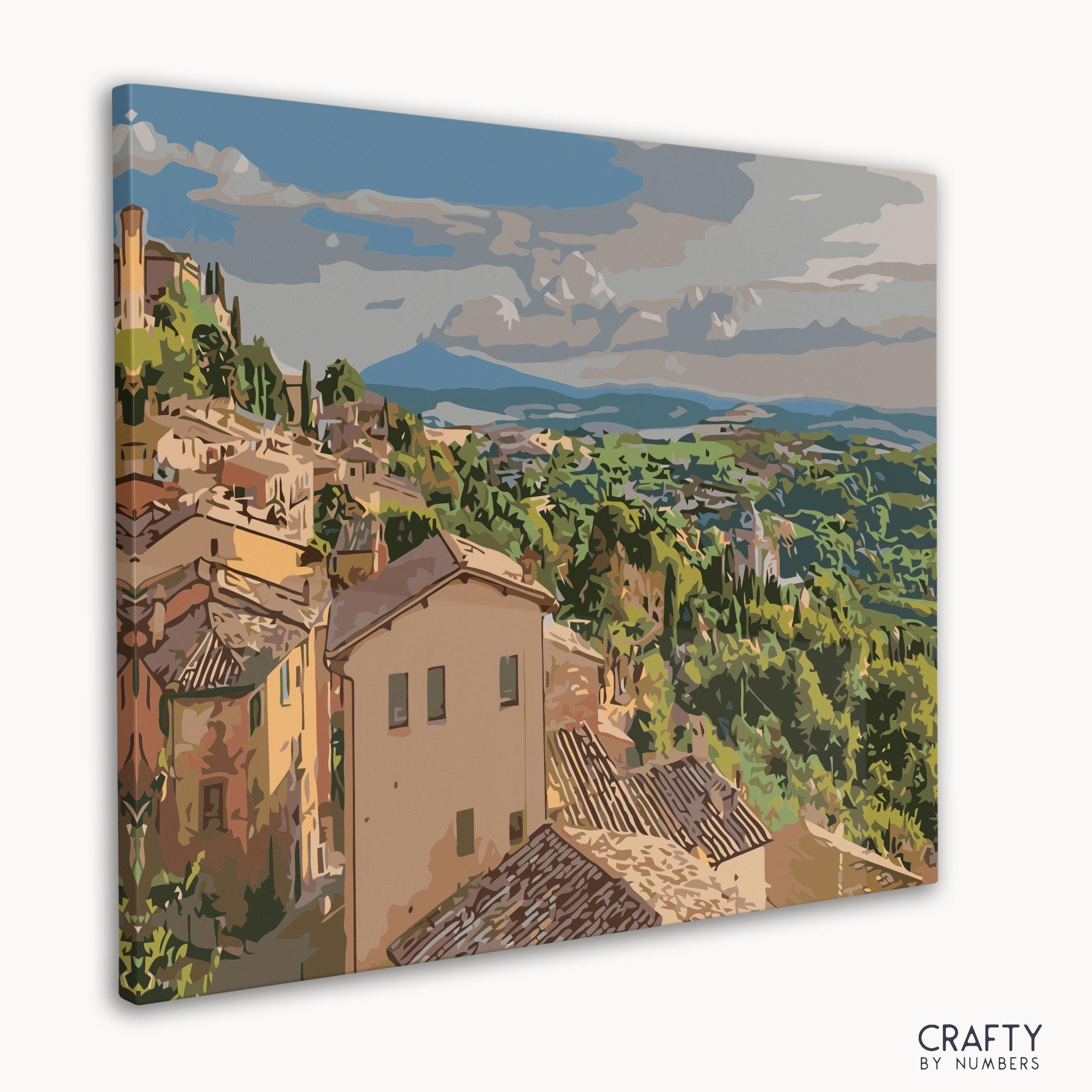Paint by numbers kit showing picturesque town in a lush Italian valley.